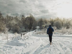 Coureur équipé d’une veste bleue sur un sentier enneigé