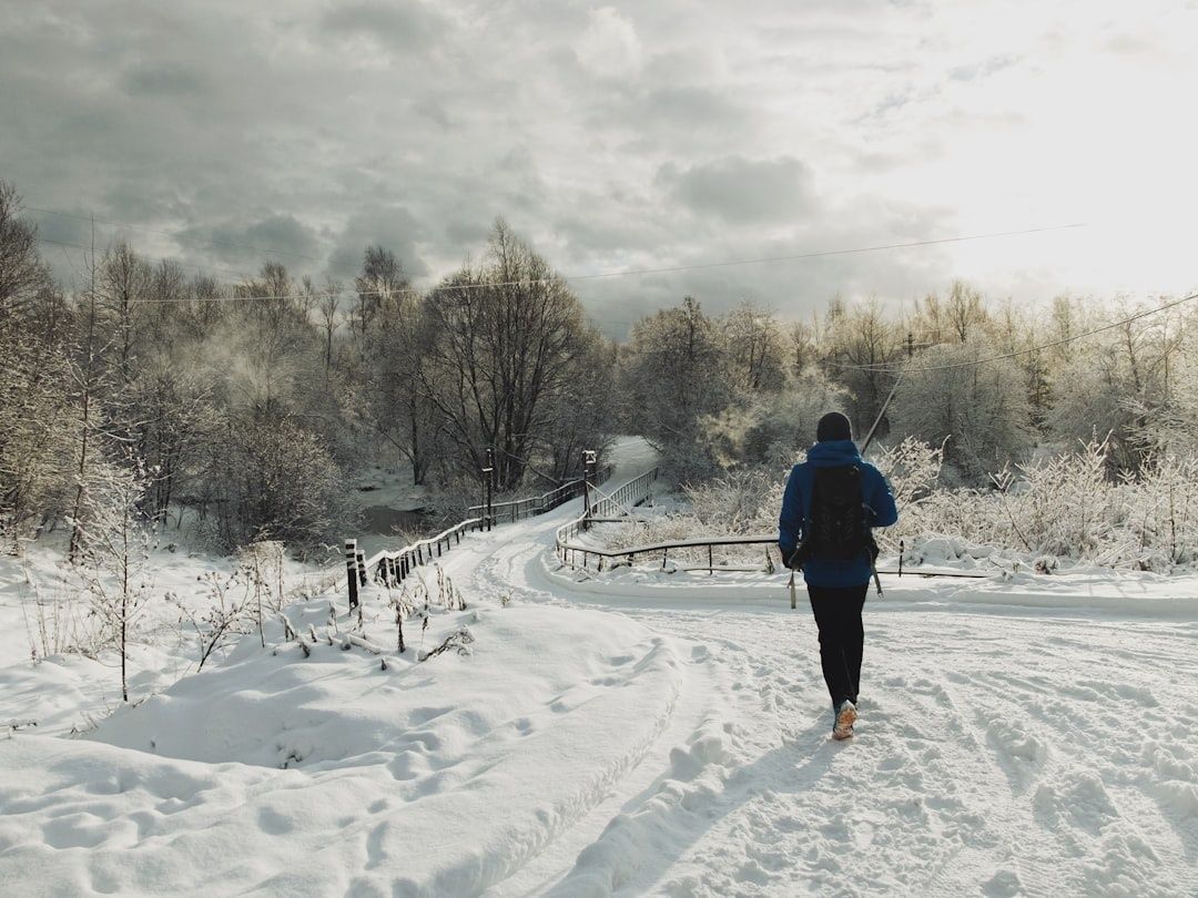 Coureur équipé d’une veste bleue sur un sentier enneigé
